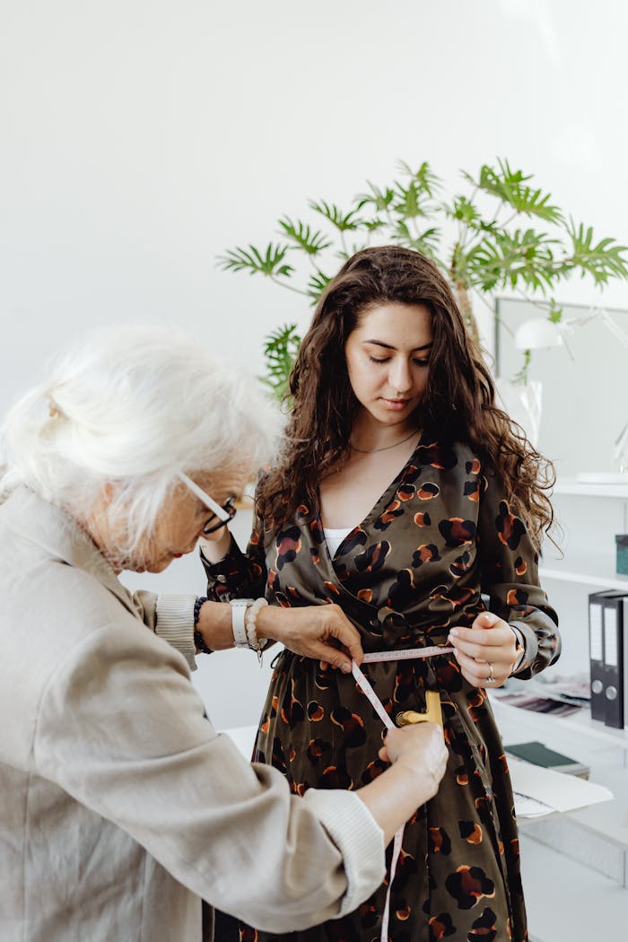 A fashion consultant measuring a young womans dress in a bright studio setting.