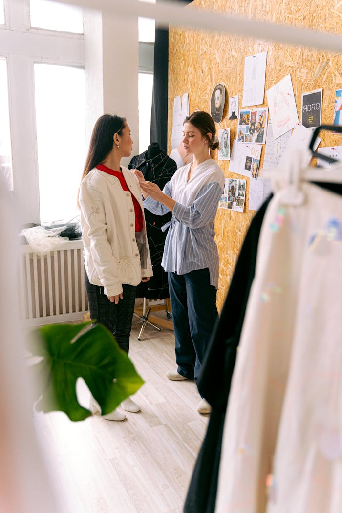 A fashion designer adjusts a models outfit in a creative studio space filled with inspiration boards.